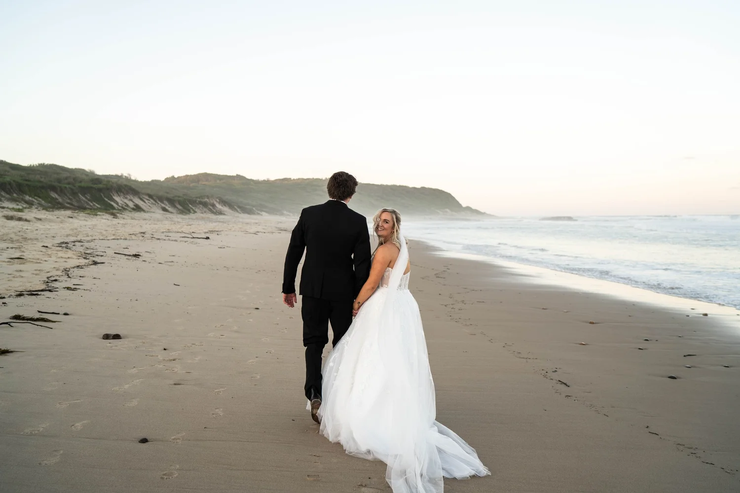 The couple walking on the beach at sunrise