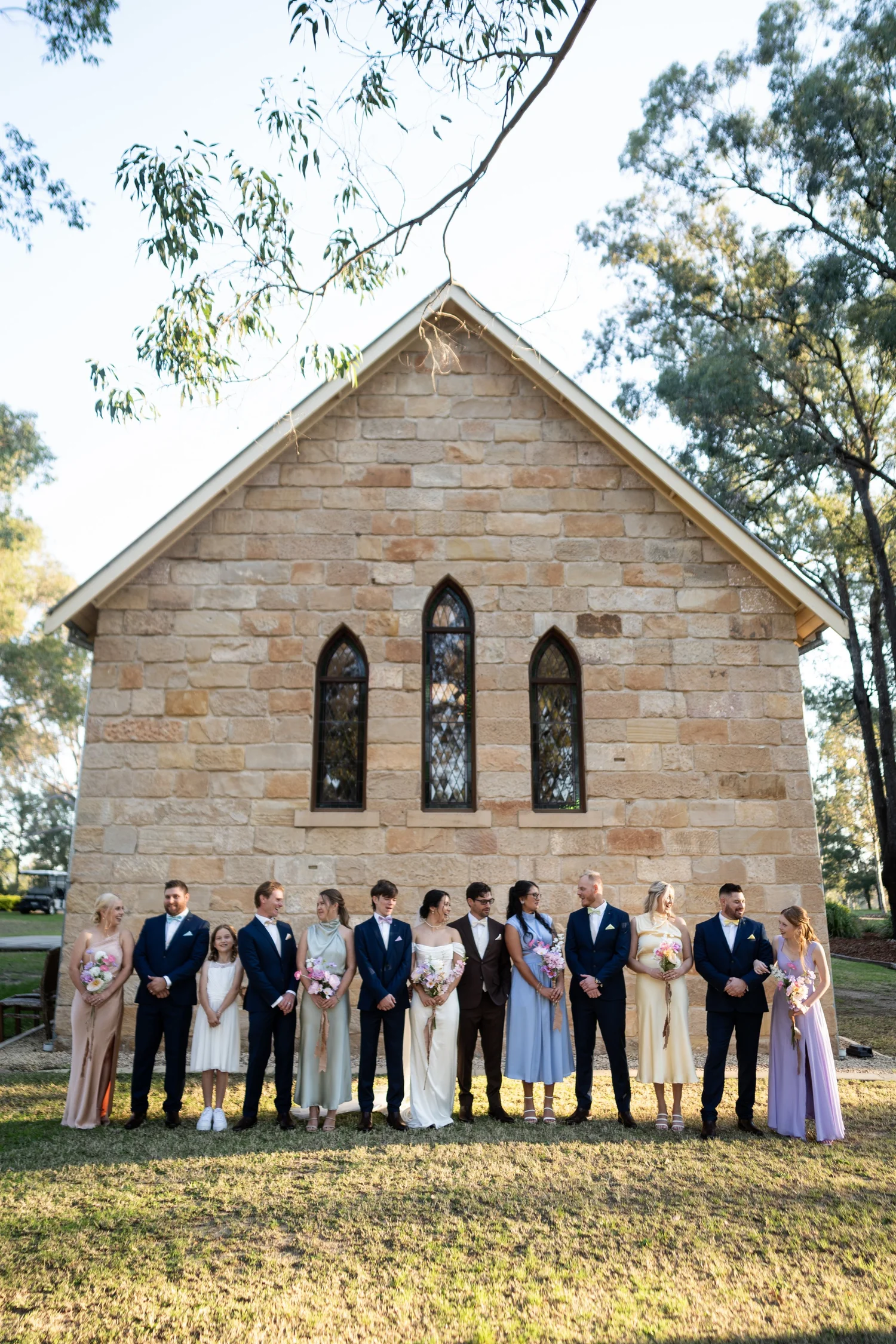 The wedding party outside a sandstone church