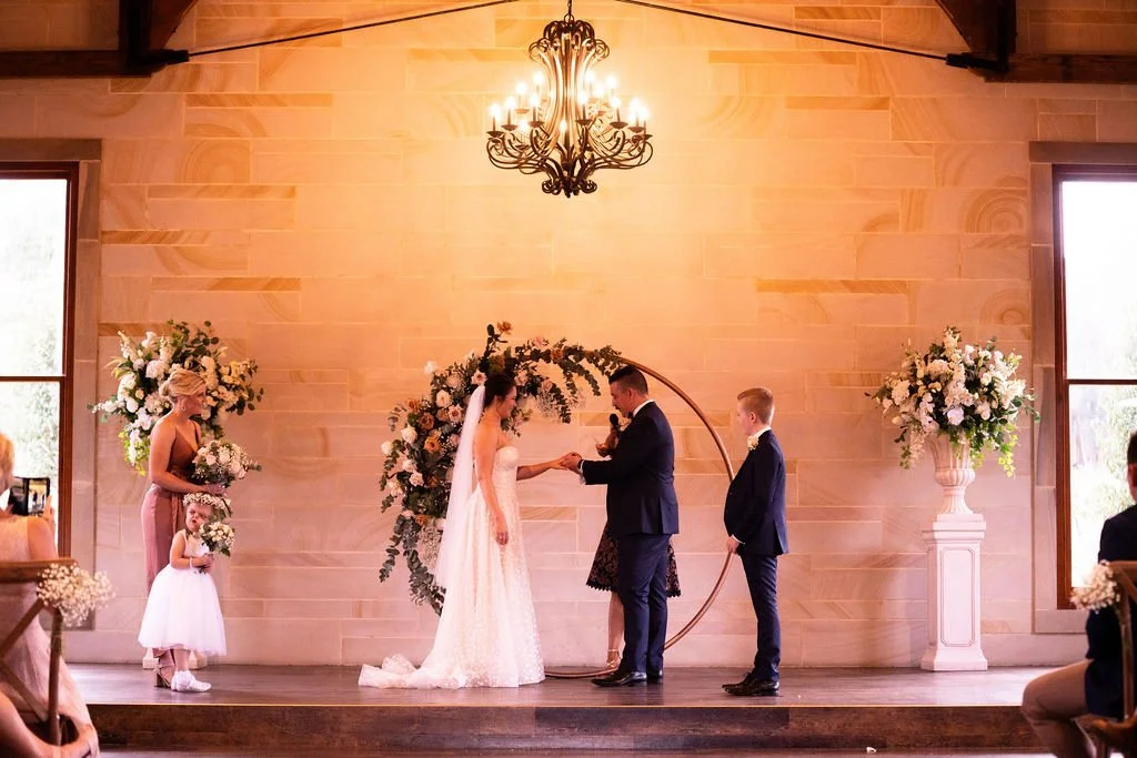 Vows under a floral arch. Wedding at Peterson House, Hunter Valley