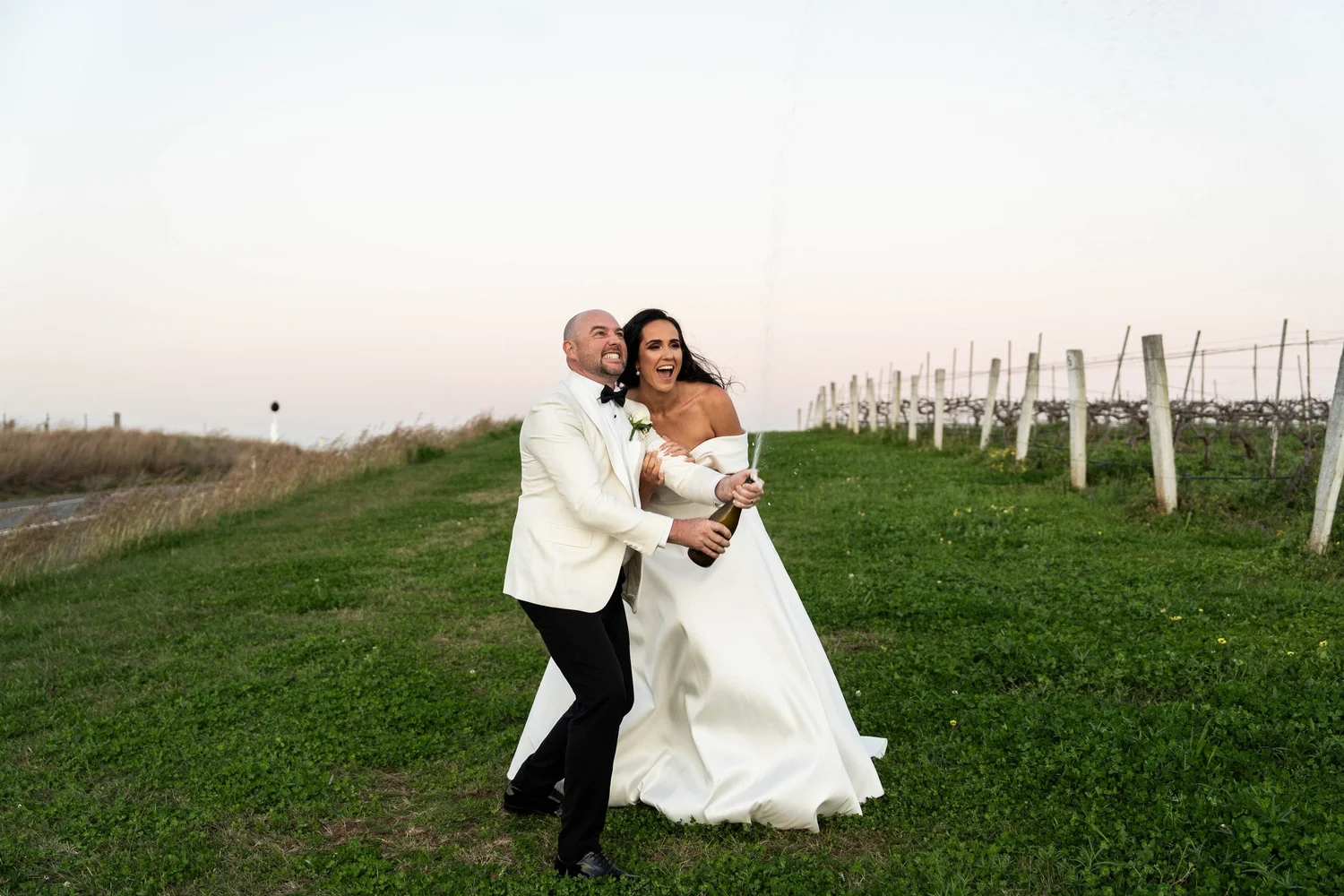 The couple walking across a paddock at sunset
