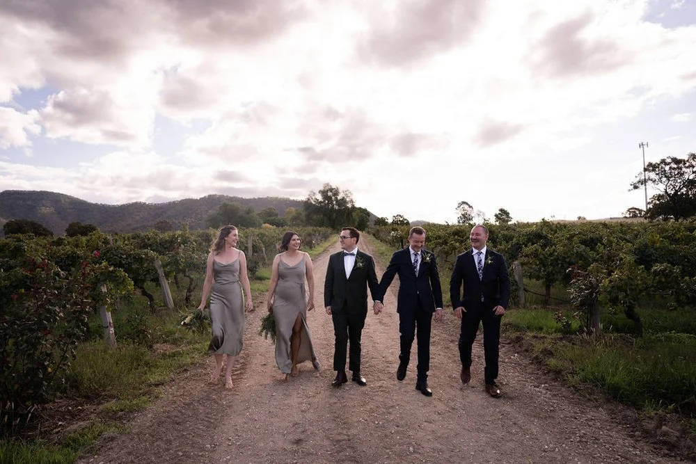 The wedding party walking down a vineyard track. Aaron & Scott's wedding at Margan Wines, Hunter Valley