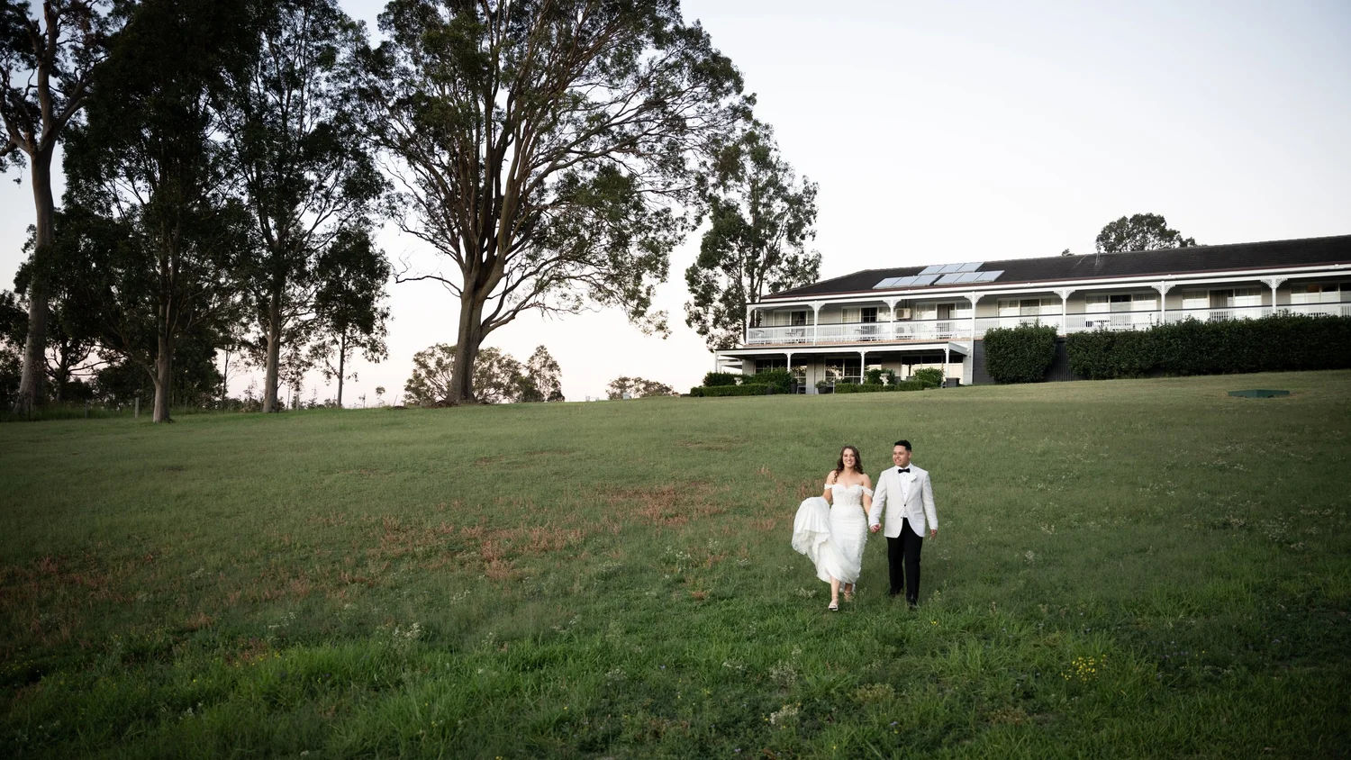The couple on the lawn with the hotel behind. Abbey & Tyran's wedding at Hunter Valley Gardens & Kirkton Park, Hunter Valley