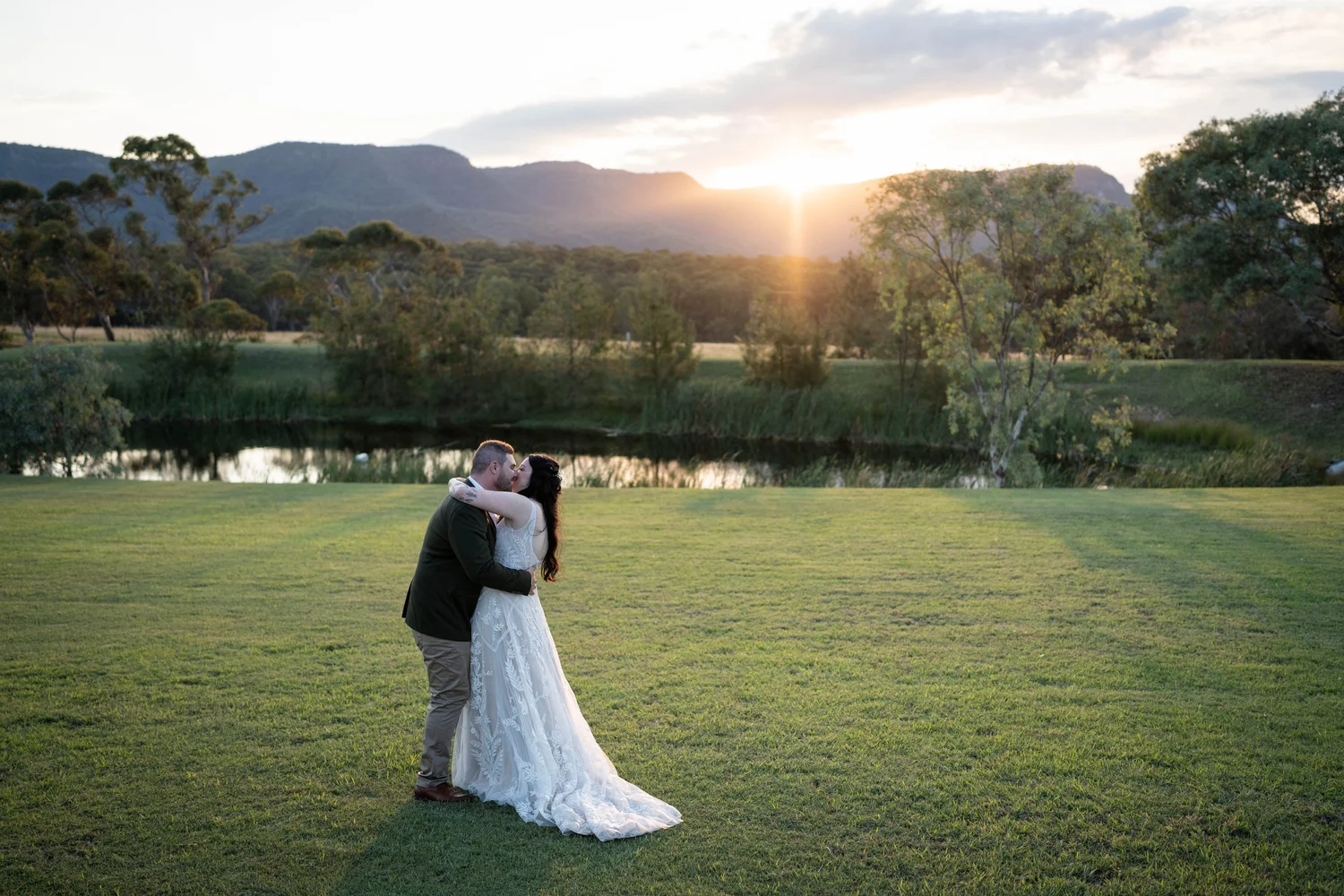 The couple on the lawn at sunset with the mountains behind. Alana & Peter's wedding at Peppers Creek, Hunter Valley