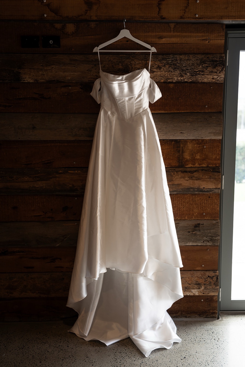 The wedding dress hanging in a timber room. Ashley & Justin's wedding at Haven Ridge, Grants Beach, Mid North Coast