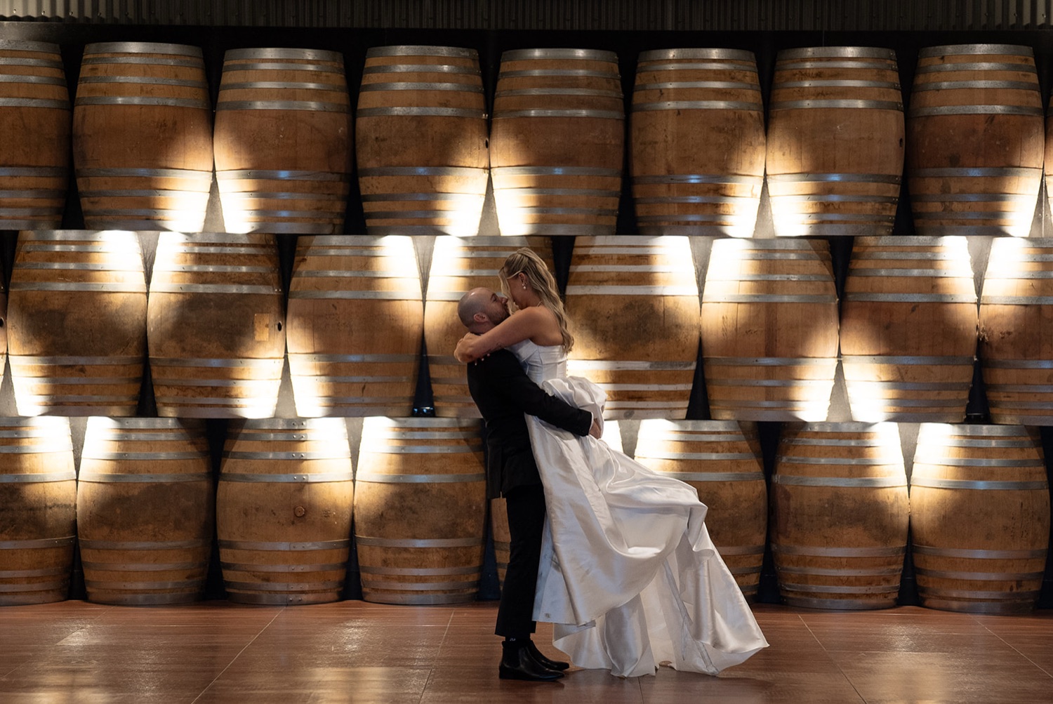 A kiss in front of candlelit wine barrels. Ashley & Justin's wedding at Haven Ridge, Grants Beach, Mid North Coast