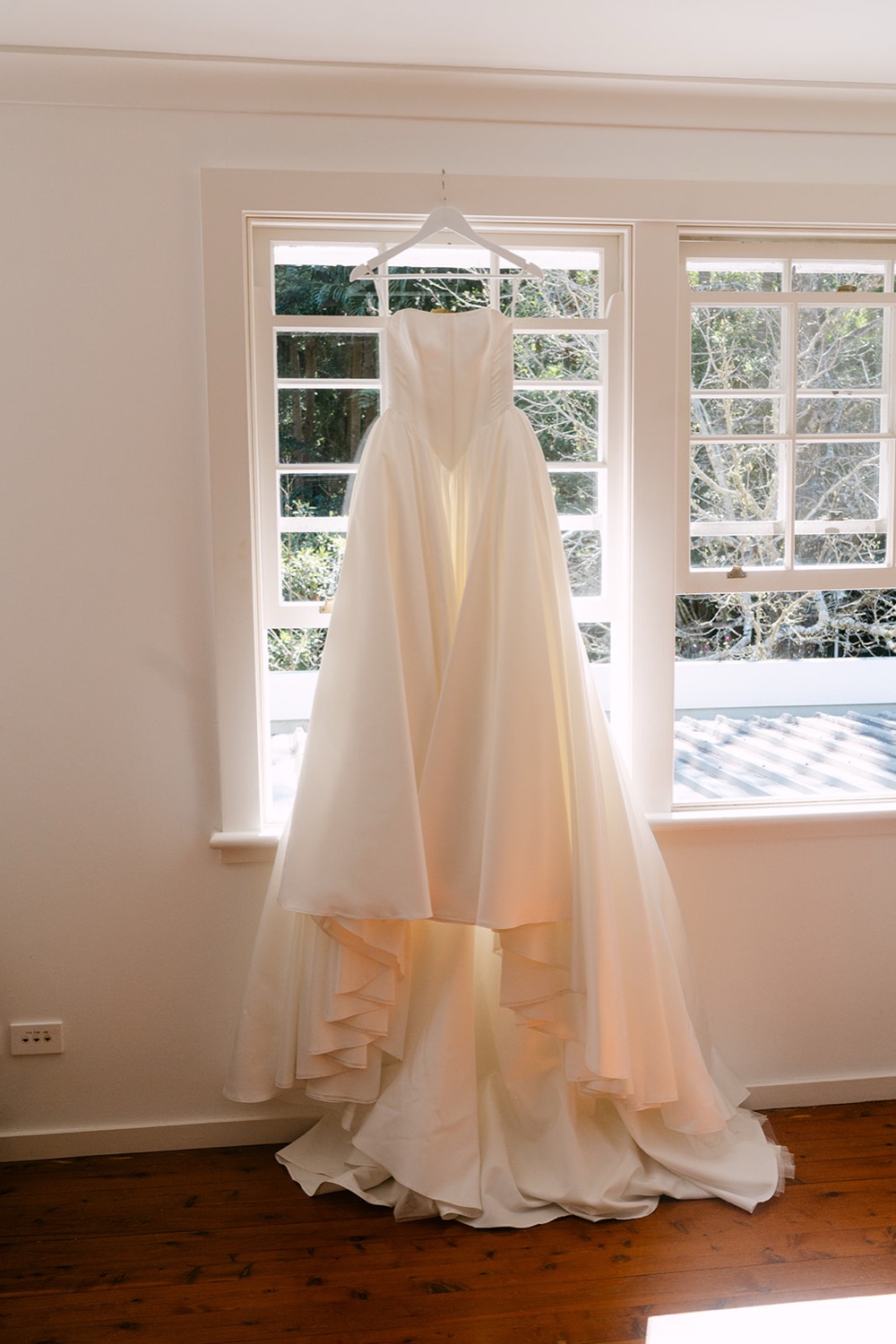 The wedding dress hanging in the window. Charlie & Lachlan's wedding at Kantara House, Central Coast