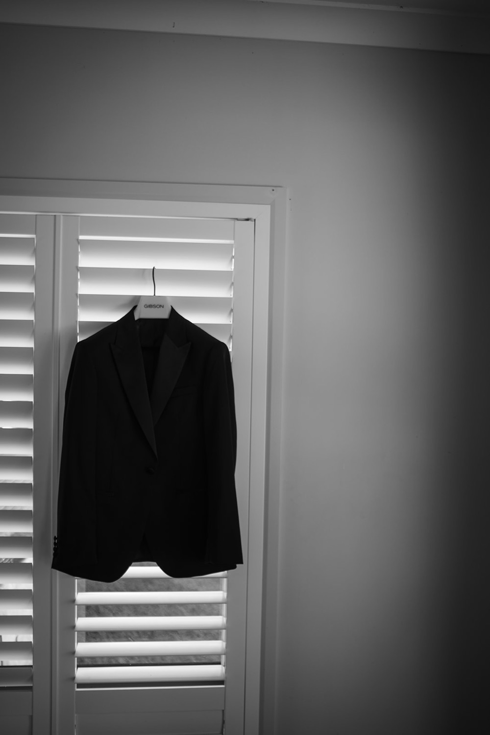 A suit hanging by the shutters, in black and white. Isabelle & Aidan's wedding at Enzo, Hunter Valley