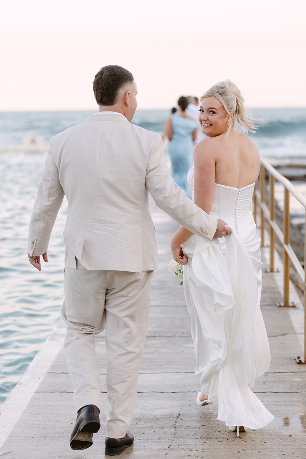 Walking along the ocean baths wall. Jasmin & Jye's wedding at Merewether Surfhouse & Ocean Baths, Newcastle