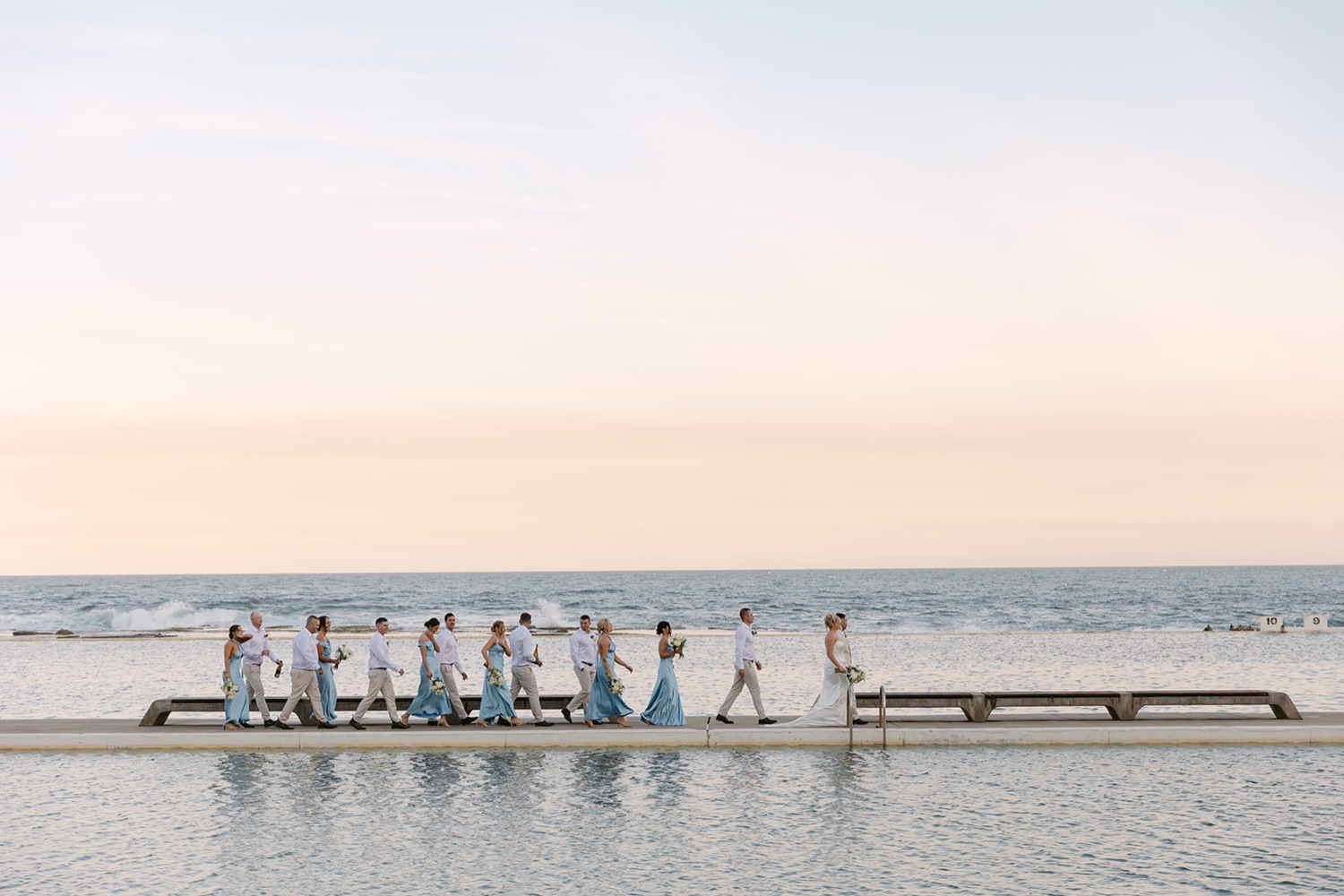 The wedding party at the ocean baths at dusk. Jasmin & Jye's wedding at Merewether Surfhouse & Ocean Baths, Newcastle