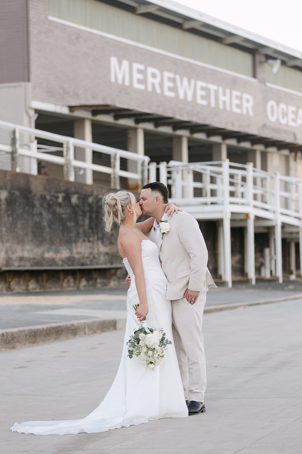 The couple below the Merewether Ocean Baths building. Jasmin & Jye's wedding at Merewether Surfhouse & Ocean Baths, Newcastle