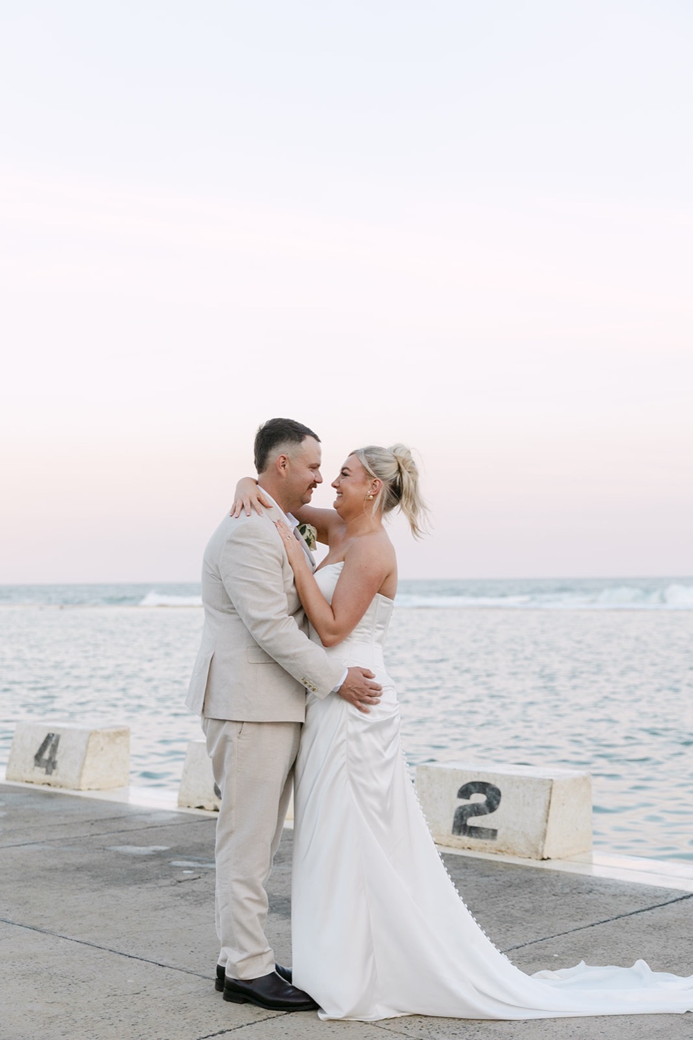 The couple on the ocean baths wall. Jasmin & Jye's wedding at Merewether Surfhouse & Ocean Baths, Newcastle