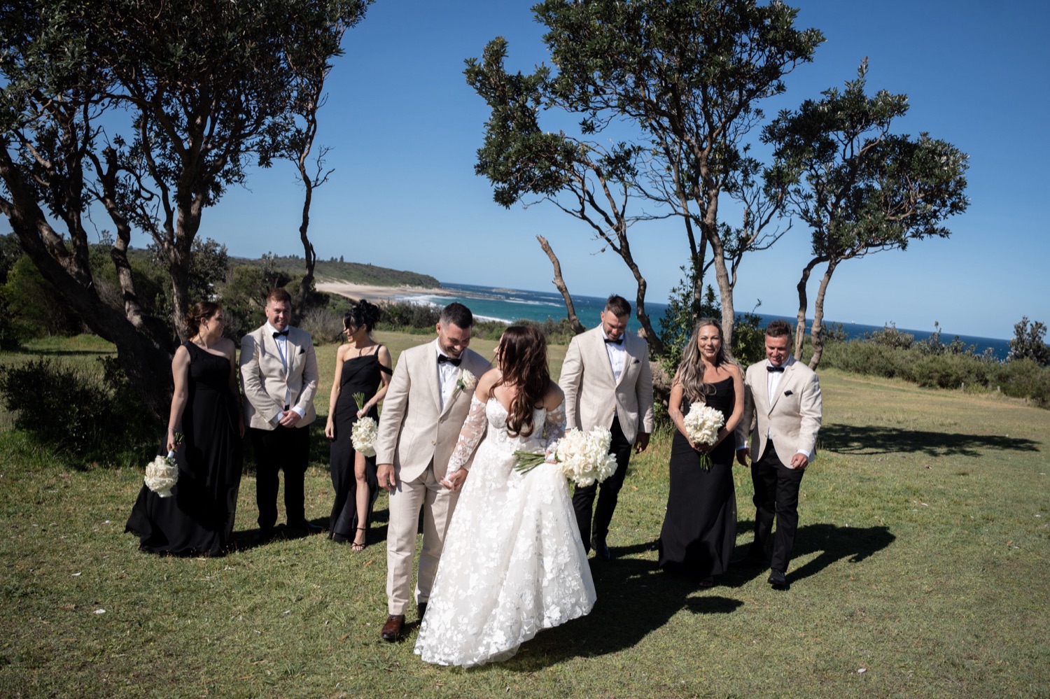 The wedding party on the clifftop lawn. Jemma & Matthew's wedding at Caves Coastal Bar & Bungalows, Newcastle