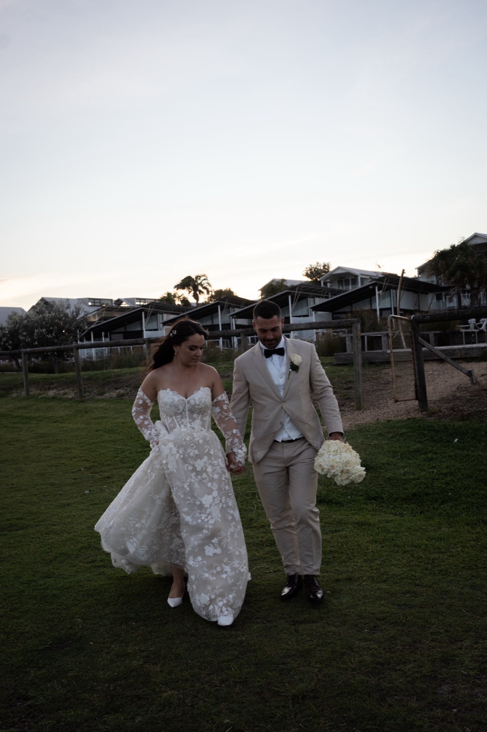 Walking across the lawn at dusk. Jemma & Matthew's wedding at Caves Coastal Bar & Bungalows, Newcastle