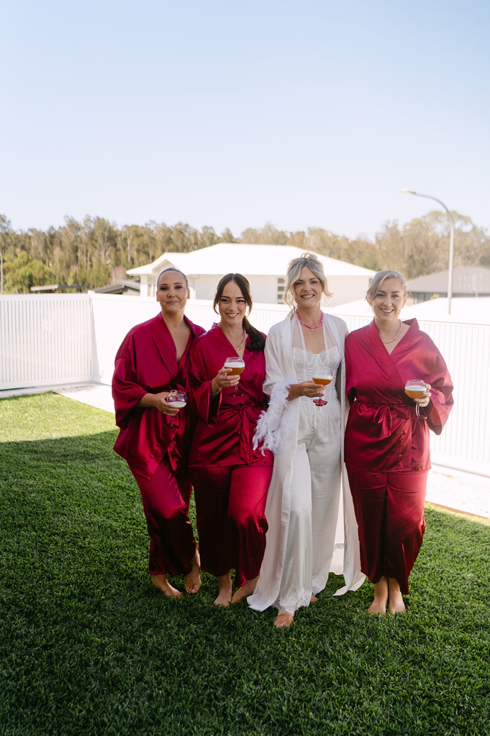 The wedding party in red and pink on the lawn. Jessica & Ricky's wedding at Chapel of Light, Port Stephens
