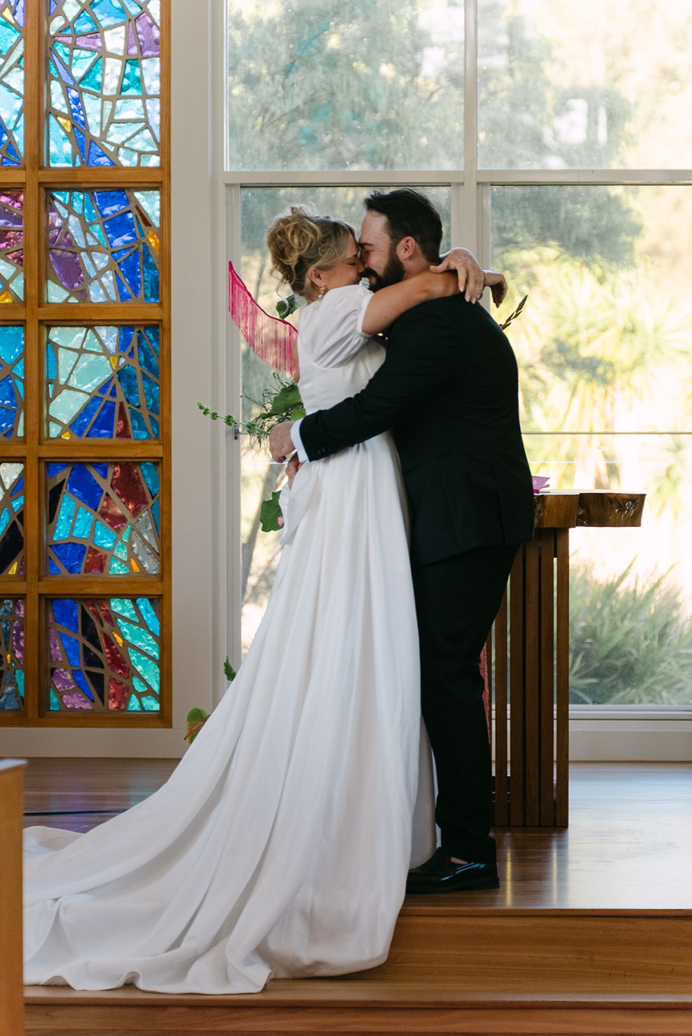 A kiss in front of the chapel's stained glass. Jessica & Ricky's wedding at Chapel of Light, Port Stephens