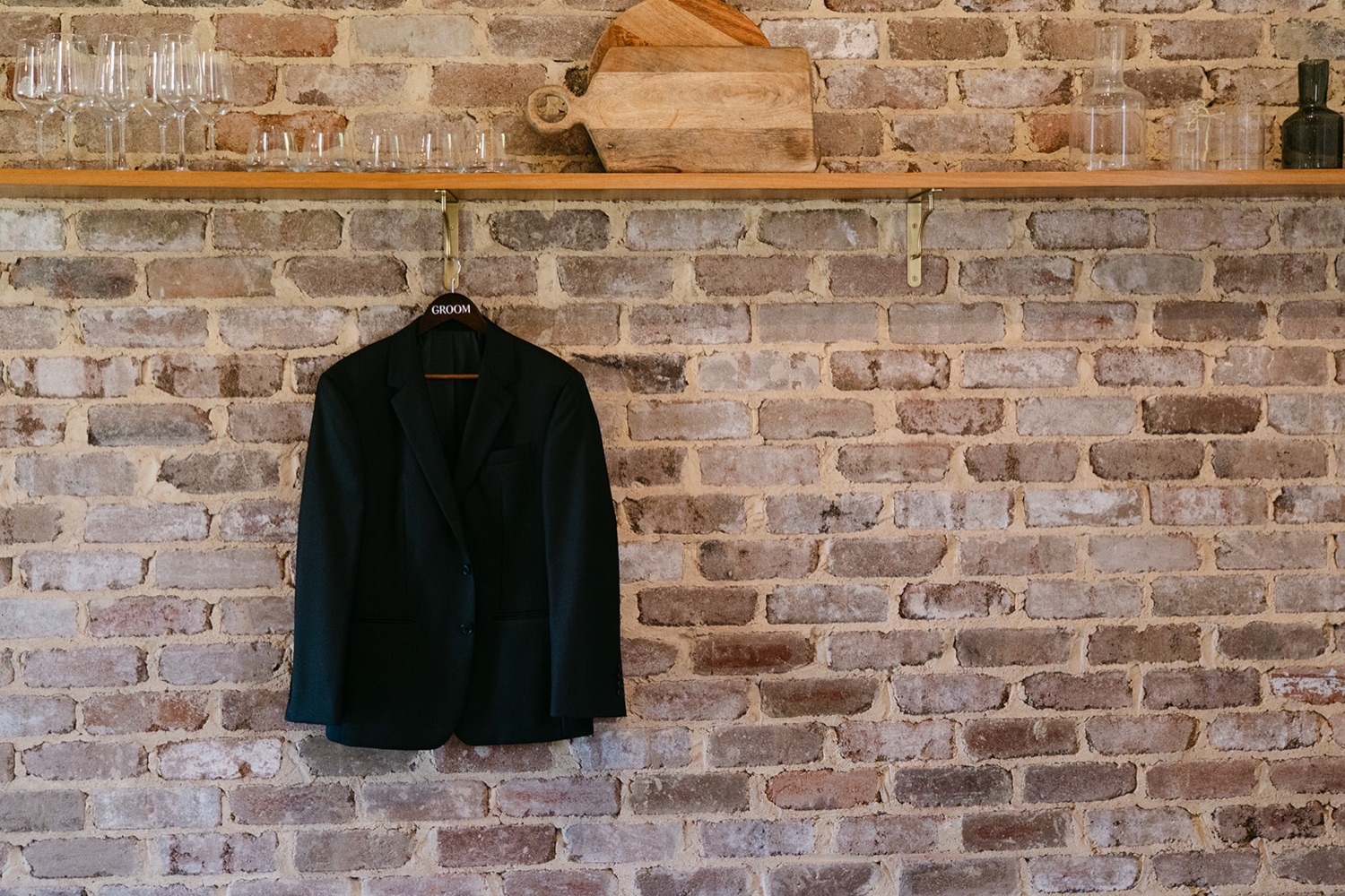 A suit jacket hanging on the brick wall. Jessie & Jack's wedding at Enzo, Hunter Valley