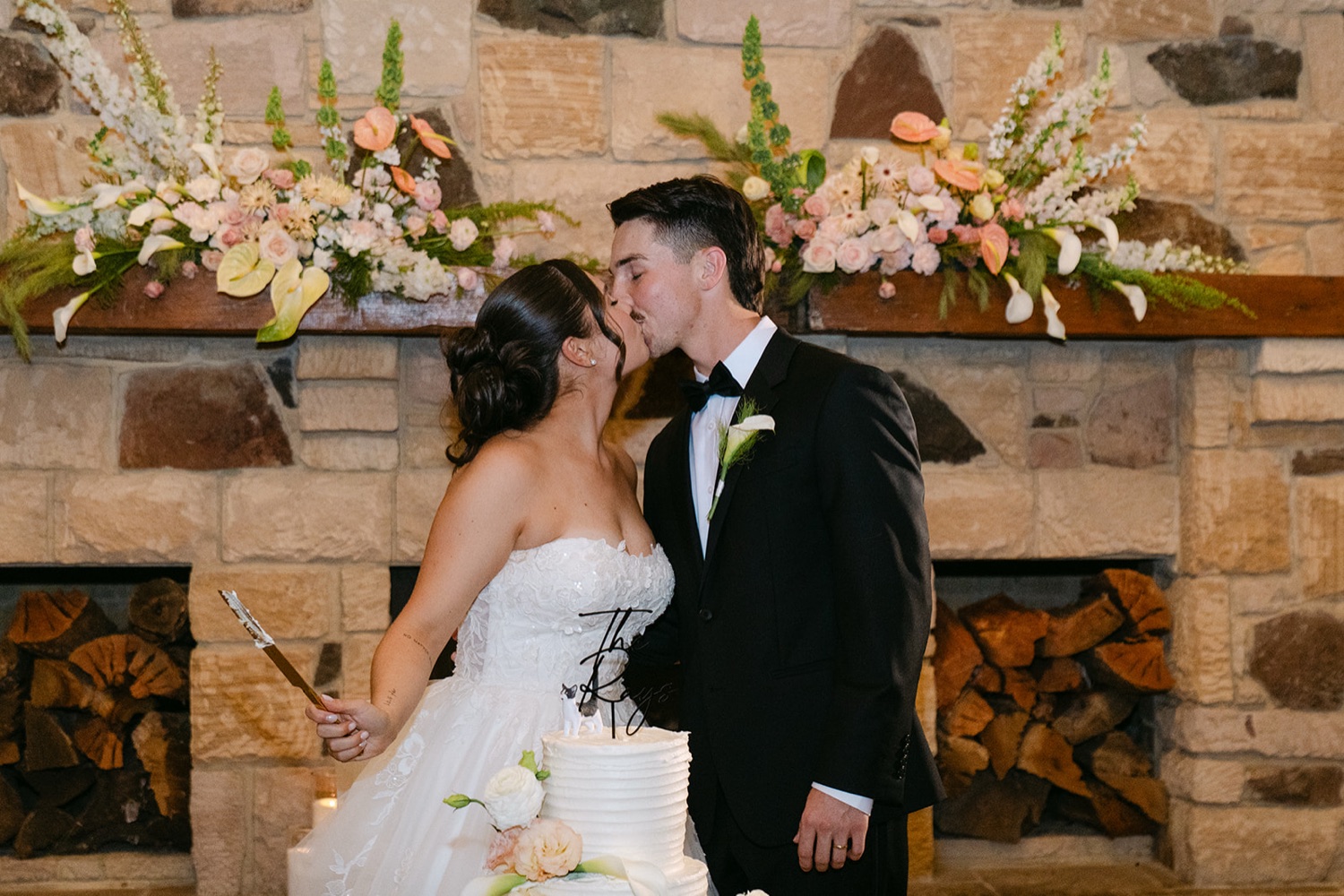 A kiss in front of the stone fireplace. Jessie & Jack's wedding at Enzo, Hunter Valley