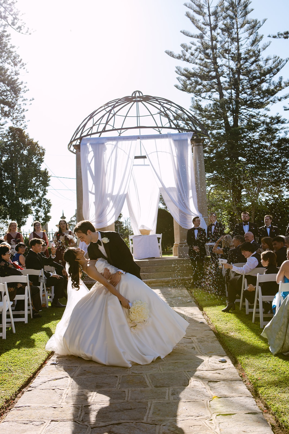 Walking down the aisle to the white gazebo. Phoebe & Cameron's wedding at Curzon Hall, Sydney