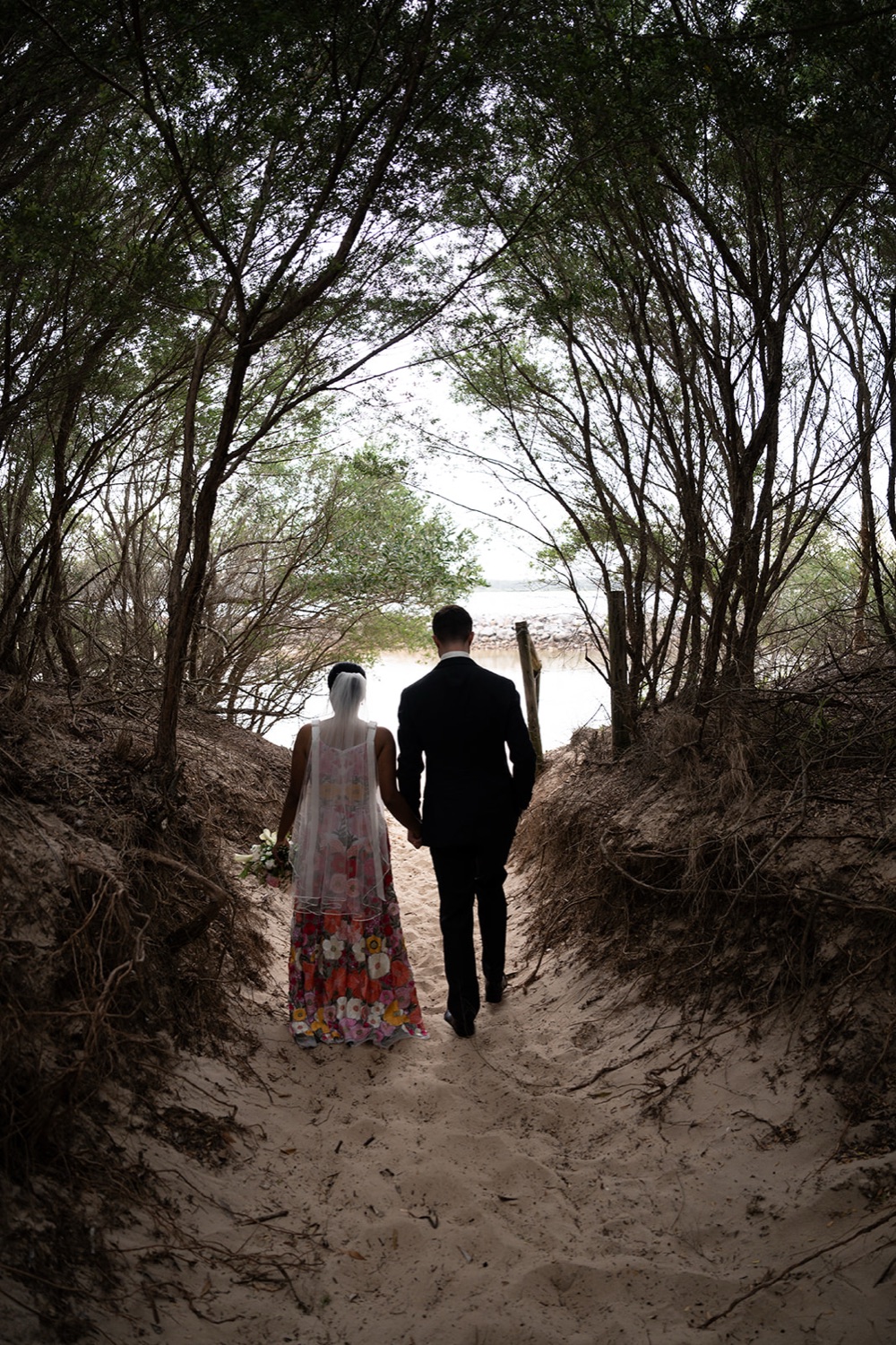 Walking down a bush track. Seneli & Grayson's wedding at Lake Macquarie Yacht Club, Belmont, Newcastle