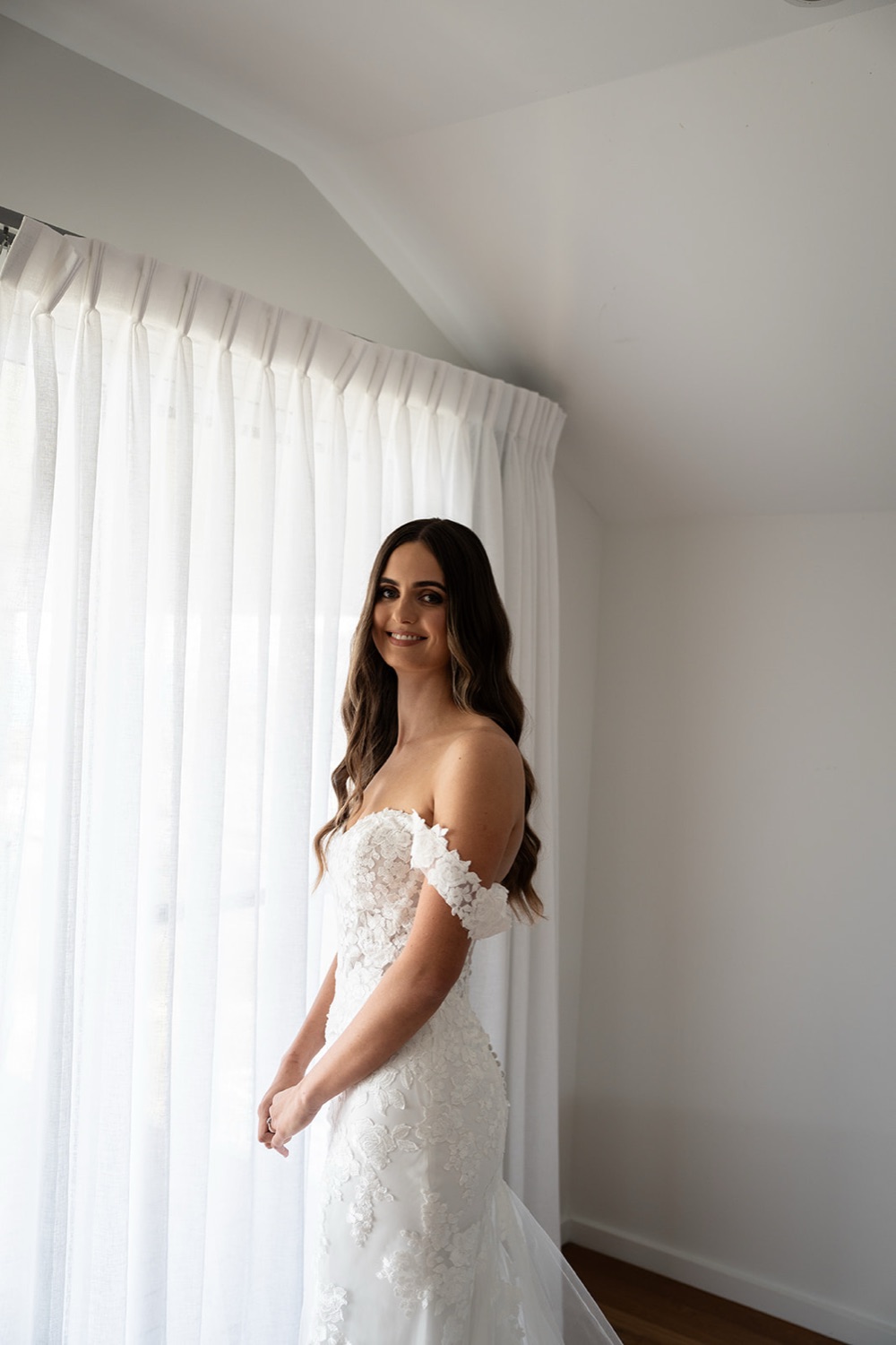 Ready in an off-the-shoulder dress. Sophie & Benjamin's wedding at Caves Coastal Bar & Bungalows, Newcastle