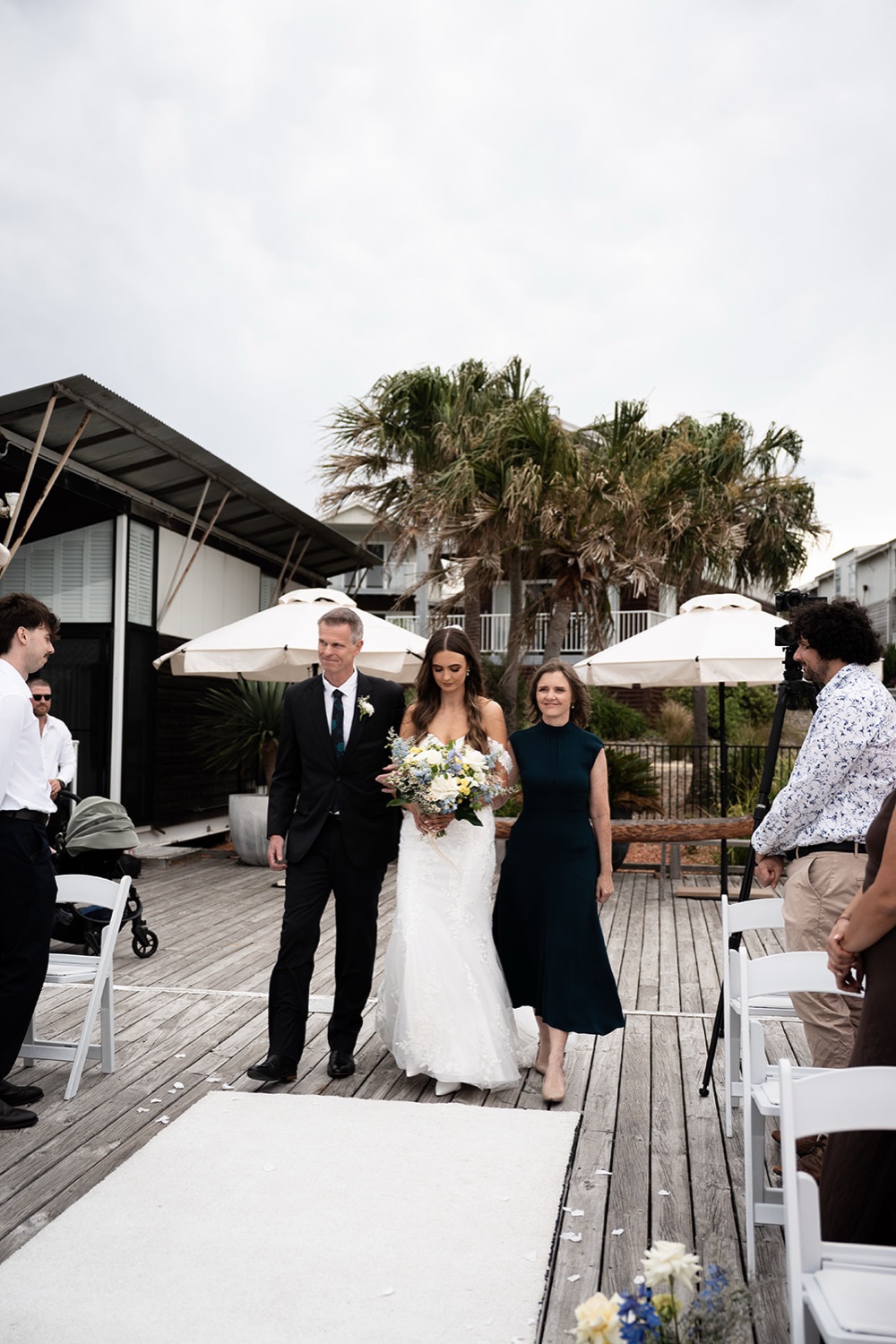 Walking down the aisle on the deck. Sophie & Benjamin's wedding at Caves Coastal Bar & Bungalows, Newcastle