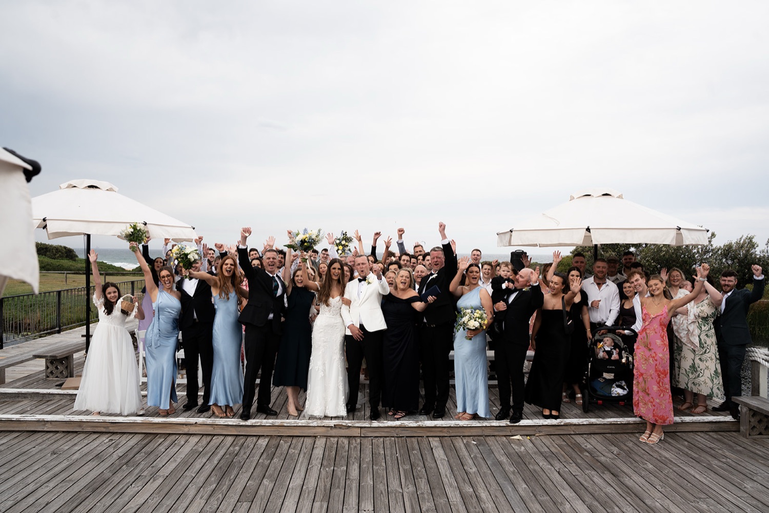 Group photo on the deck. Sophie & Benjamin's wedding at Caves Coastal Bar & Bungalows, Newcastle