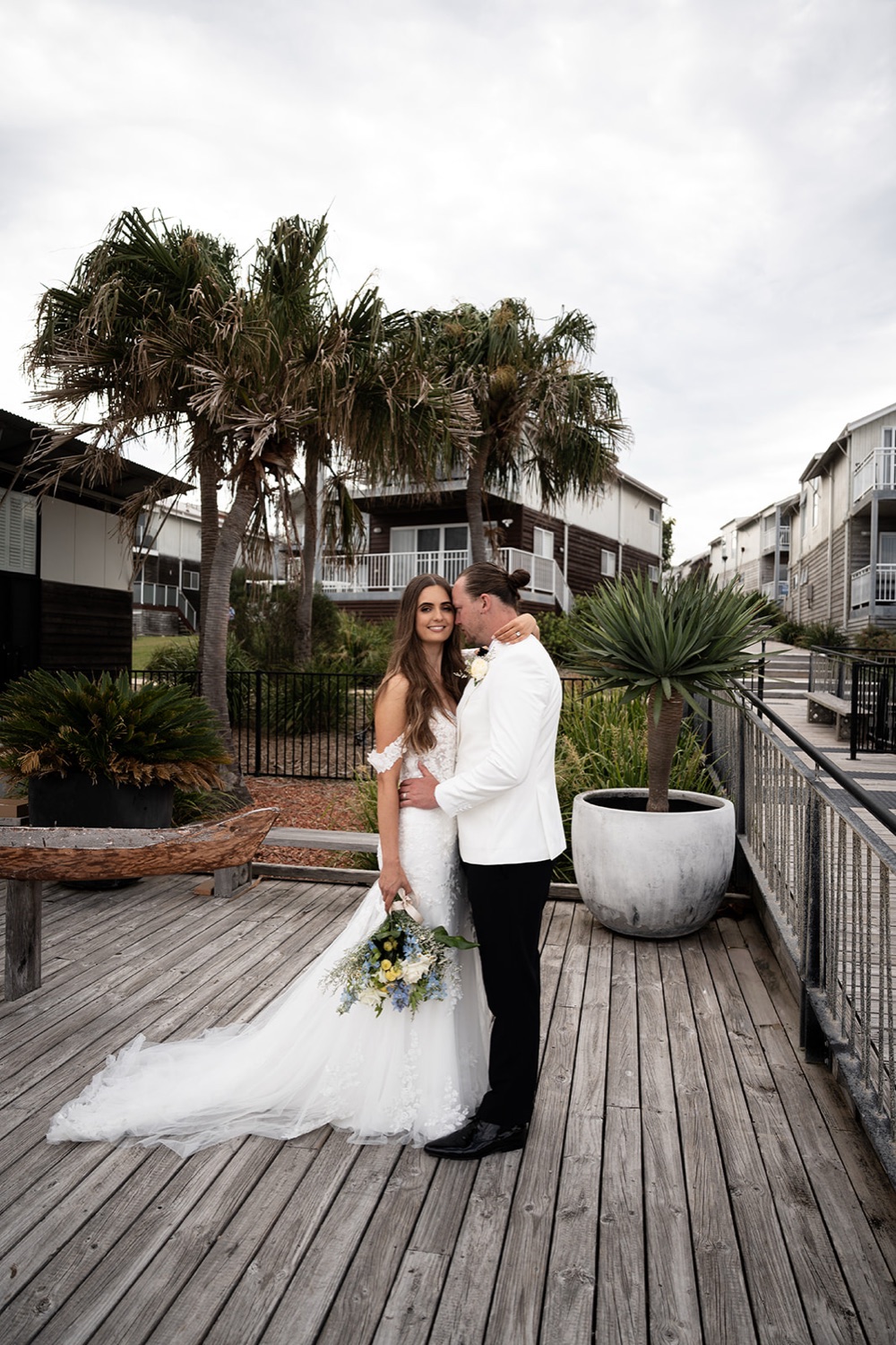 The couple on the deck among the palms. Sophie & Benjamin's wedding at Caves Coastal Bar & Bungalows, Newcastle