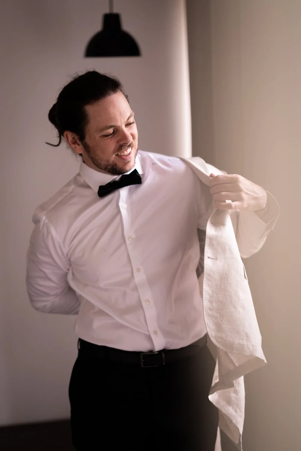 Getting ready, putting on a bow tie. Tamara & Sam's wedding at Kantara House, Central Coast