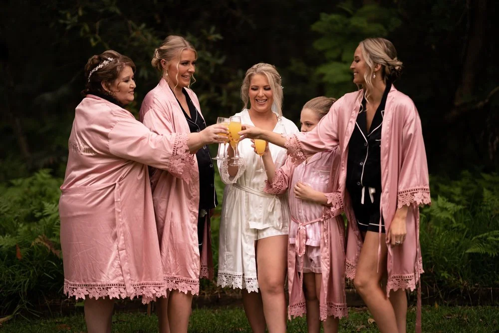 The wedding party in pink robes in the garden. Tamara & Sam's wedding at Kantara House, Central Coast