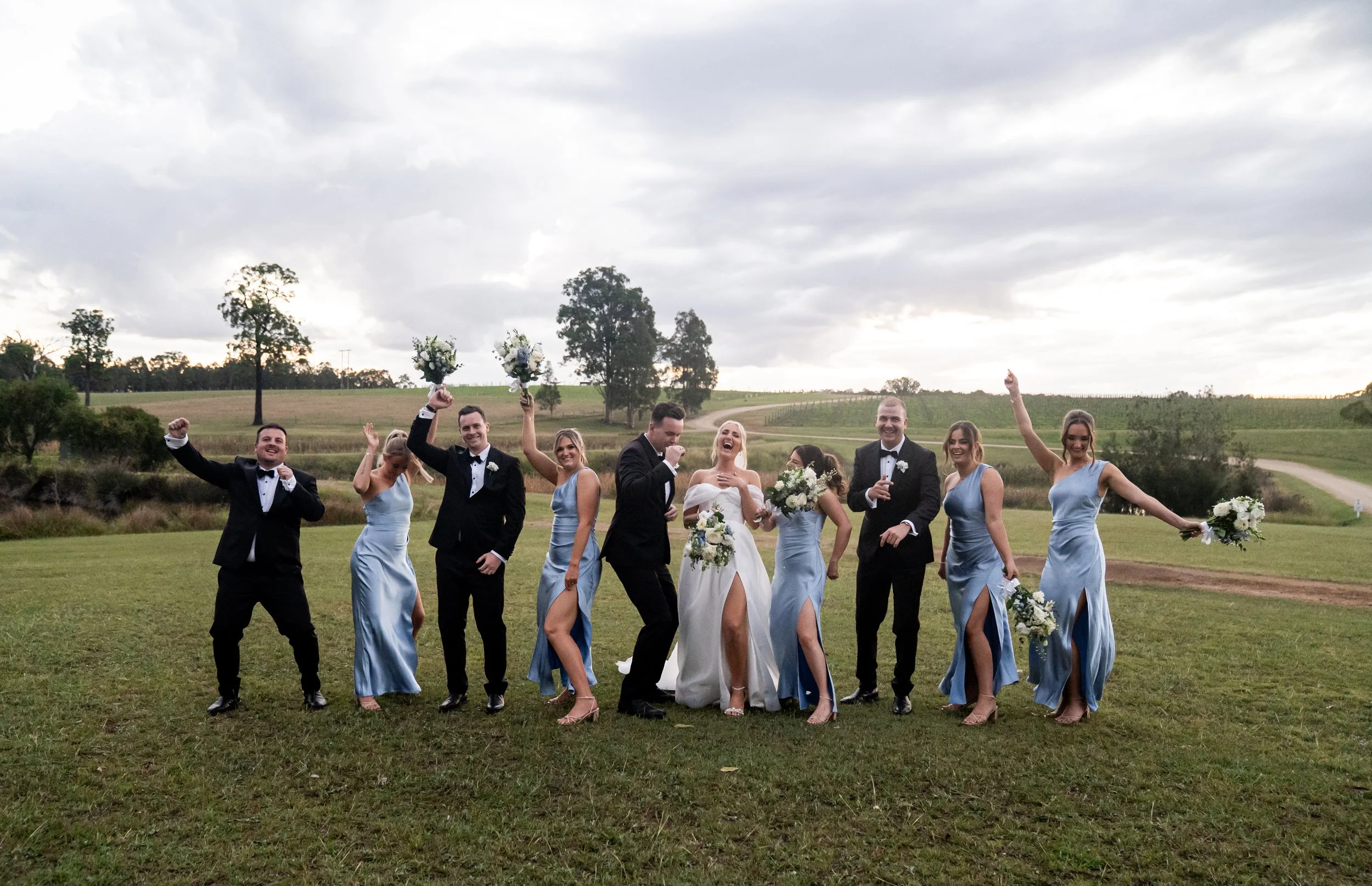The wedding party jumping in a field