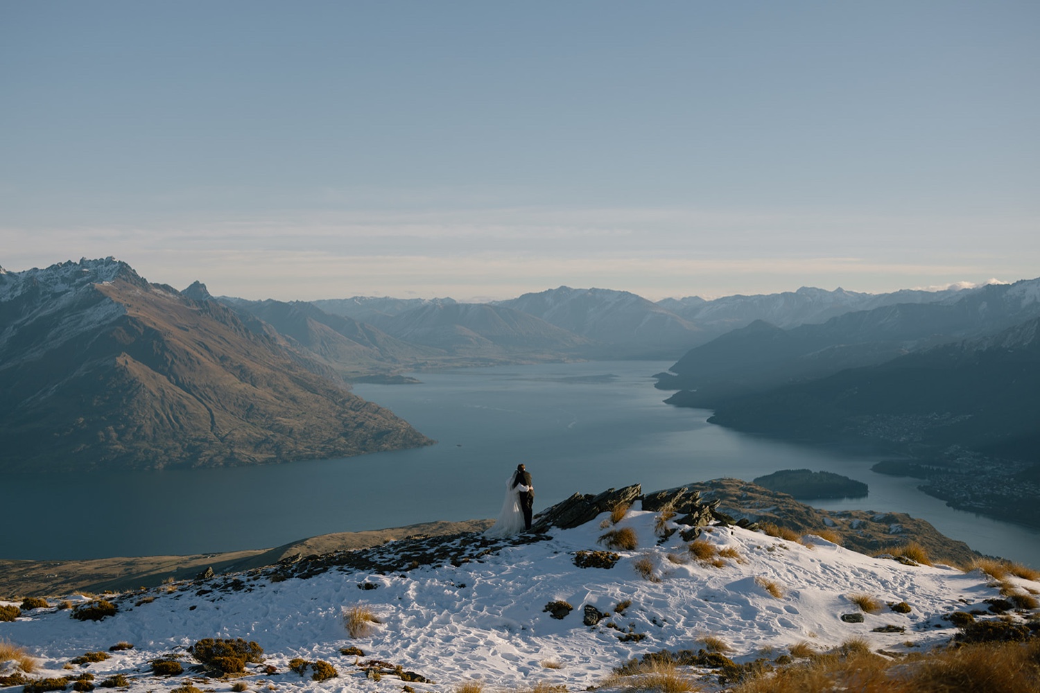Chris and Casey on a snowy peak above a lake