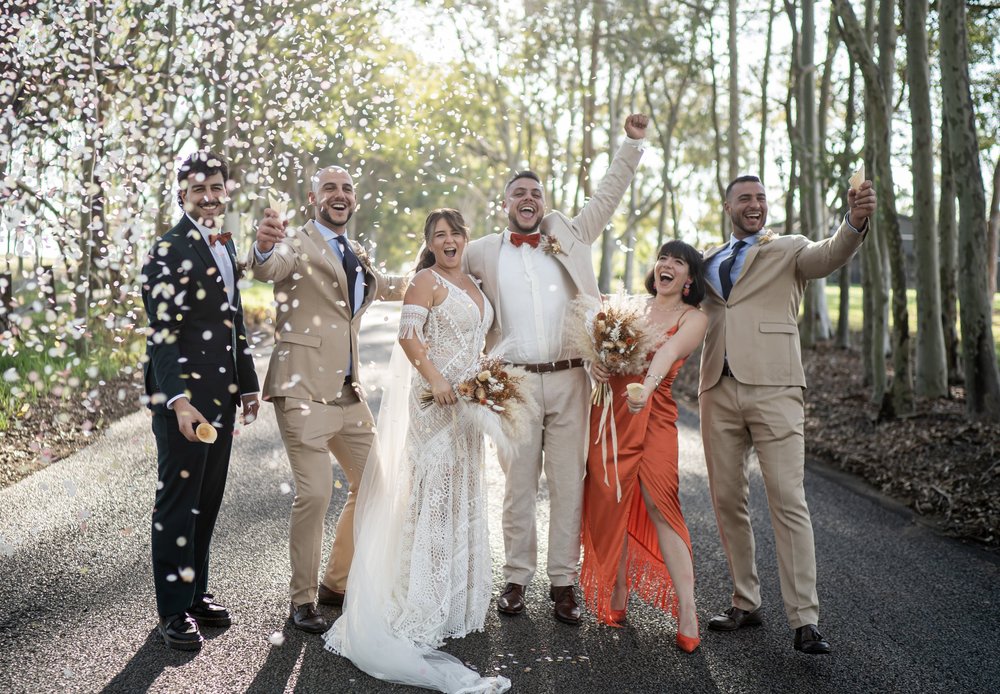 The wedding party on a tree-lined drive